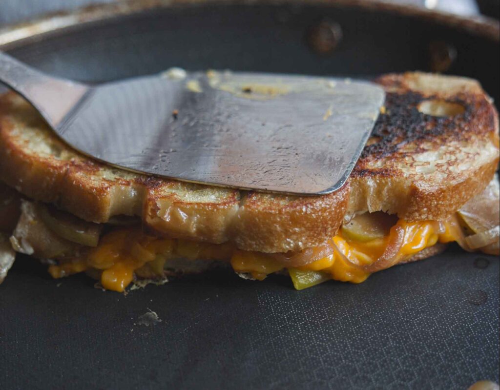 pressing spatula down on top of vegan grilled cheese sandwich